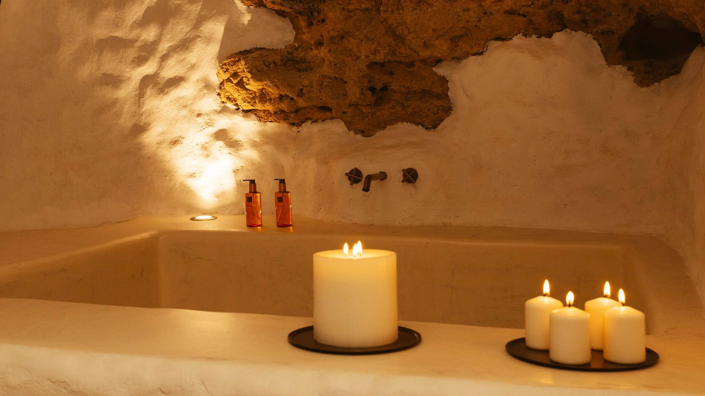 Bañera de obra de Canelita bajo un techo de roca natural, con luz cálida